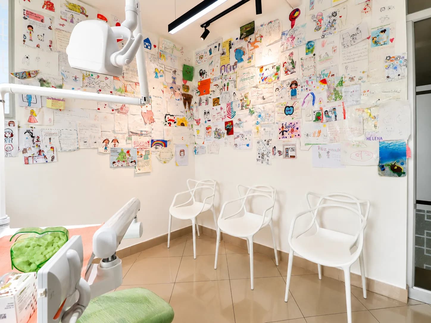 Consultorio de la Dra. Jennifer Cáceres con una pared cubierta por dibujos de sus pacientes infantiles